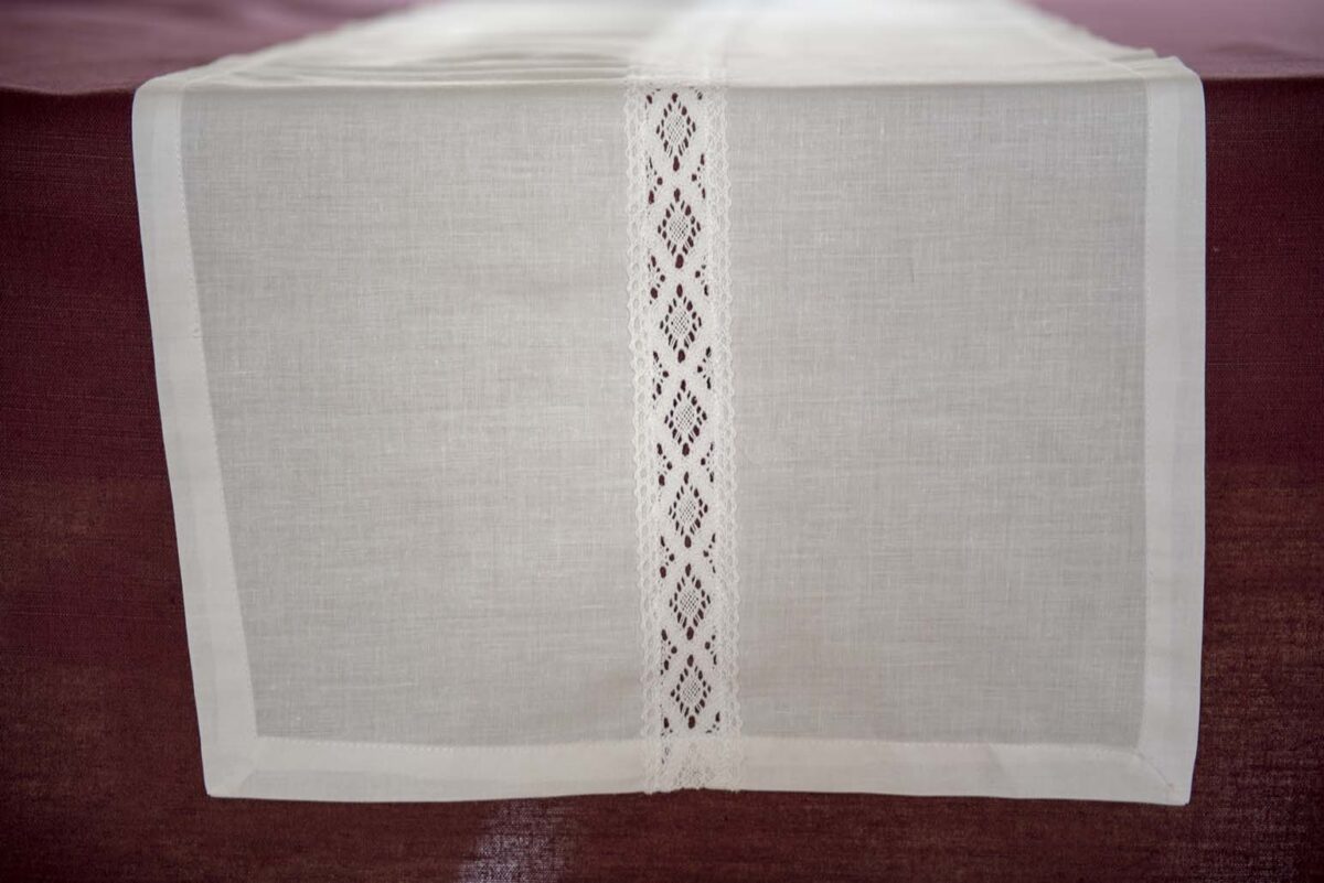 white cotton table runner adorned with a strip of lace across the middle of it