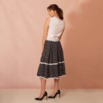 model wearing a black and white polka dot flared skirt adorned with bobbin lace