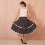 model wearing a black and white polka dot flared skirt adorned with bobbin lace