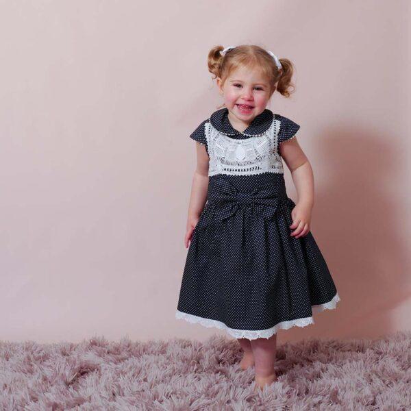 sweet girl wearing a navy blue polka dot dress with a lovely peter pan collar adorned with handmade lace trims