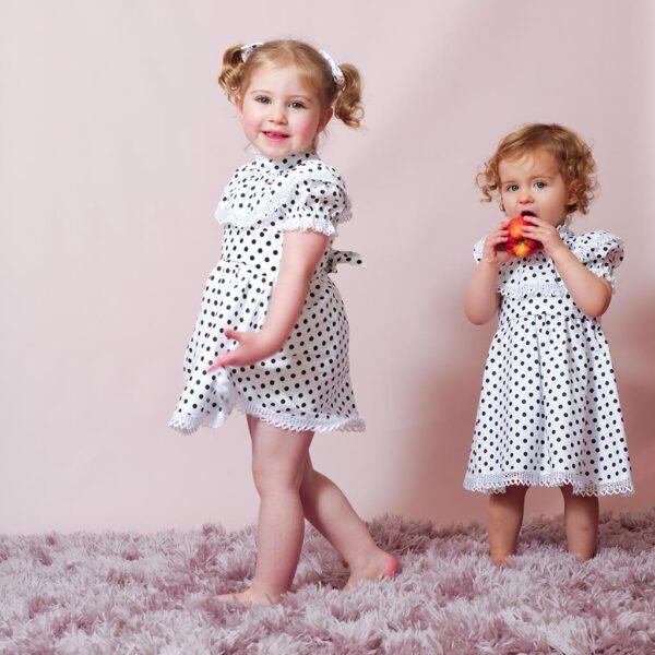 two sweet little sisters wearing navy blue polka dot matching dresses